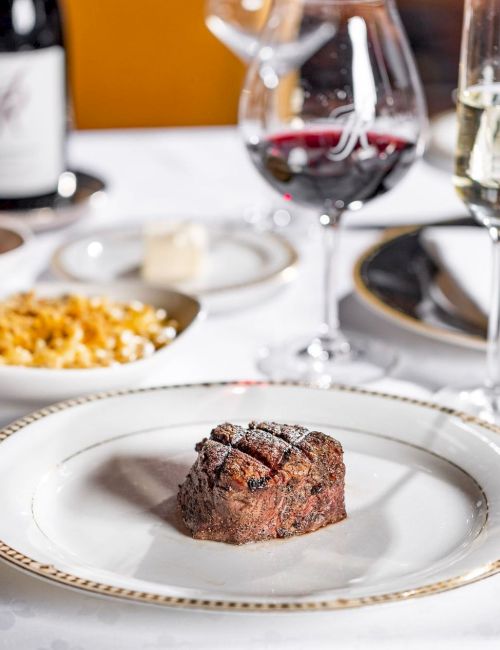 A gourmet restaurant table set with steak, side dishes, and sparkling wine glasses for an elegant dinner.