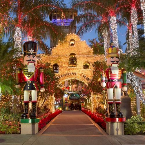 A holiday garden lit with colorful fireworks, featuring towering nutcracker statues flanking a glowing &ldquo;Sugar&rdquo; house entrance.