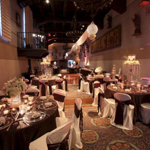 A decorated banquet hall with round tables, candles, flowers, and chandeliers&mdash;looks like a wedding reception.