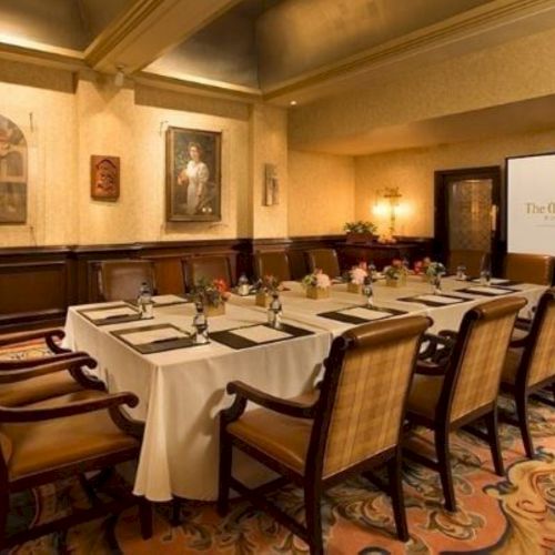 A hotel conference room set with banquet tables and chairs, decorated walls, and a screen showing &ldquo;The Mission Inn&rdquo; for presentations.