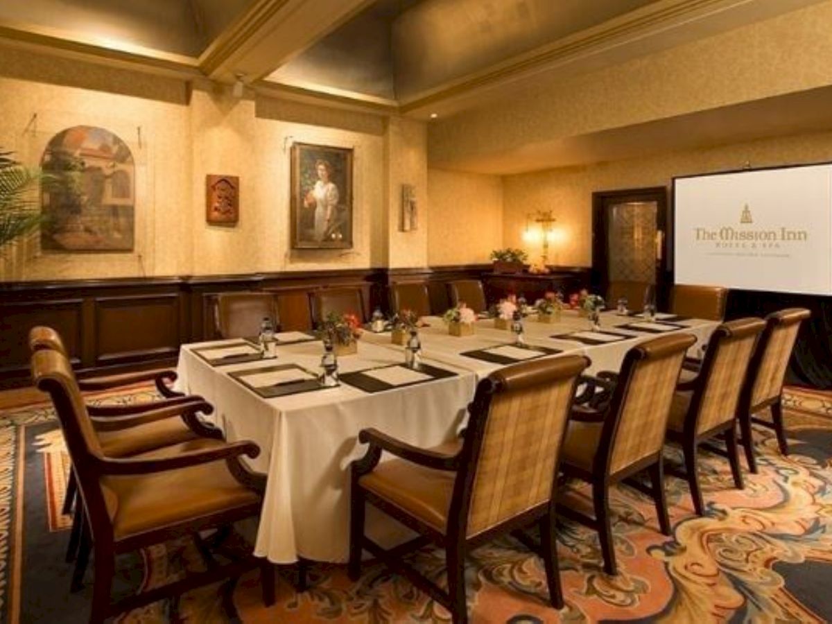 A hotel conference room with set tables, upholstered chairs, wall art, and a presentation screen for meetings, .