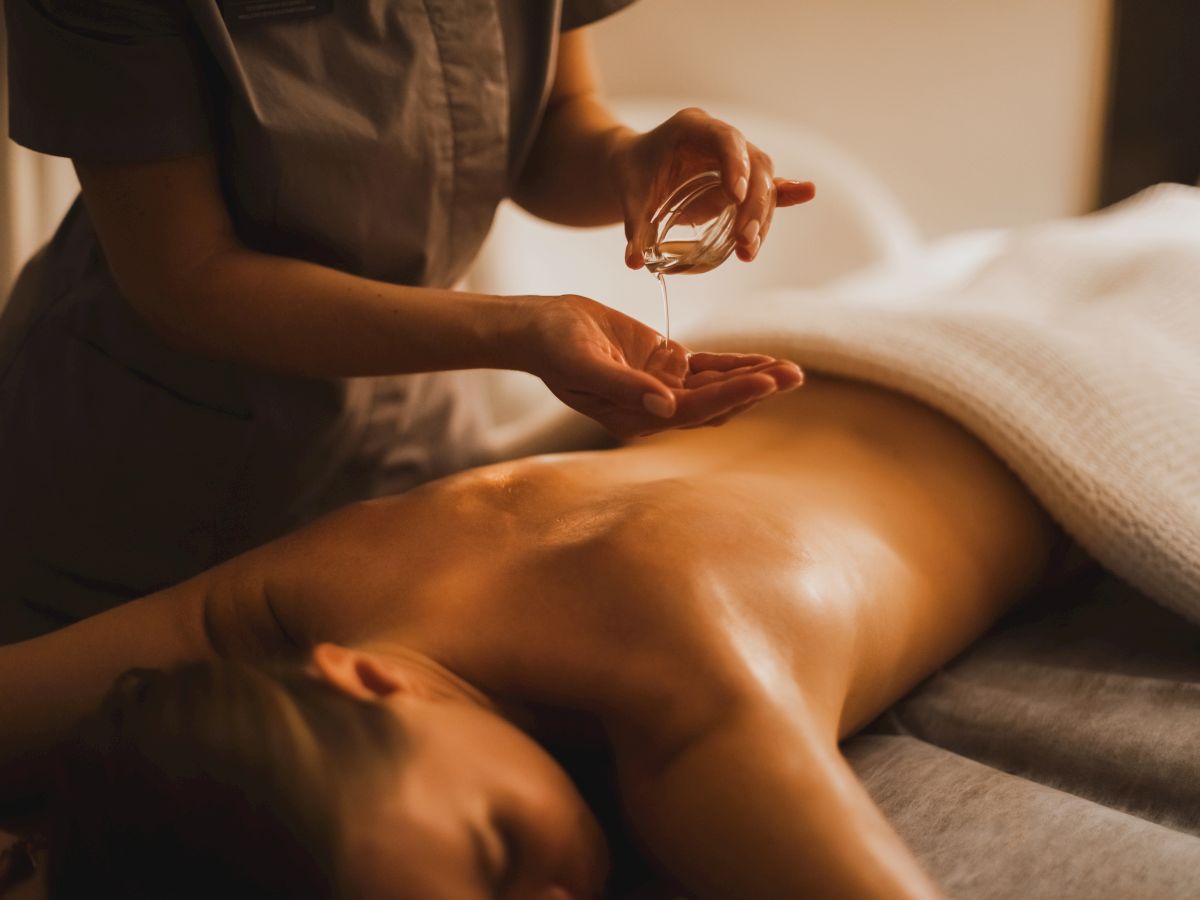 A therapist pours massage oil and rubs it onto a client&rsquo;s back during a relaxing massage.